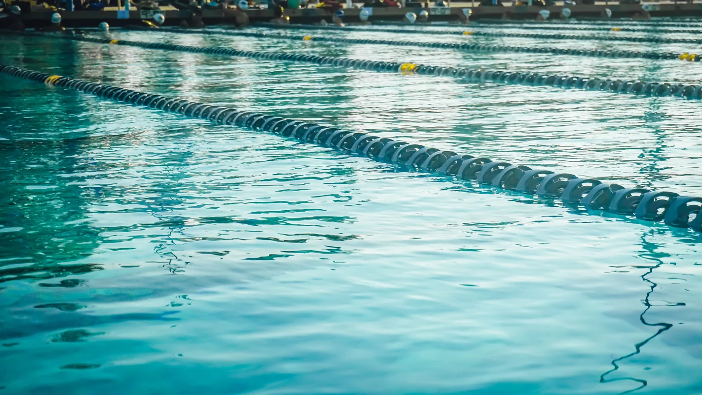 蓝色泳池水面与分隔泳道的浮标，游泳主题配图，非 Goldfish Swim School 场地照片（课程示意图，非机构现场）